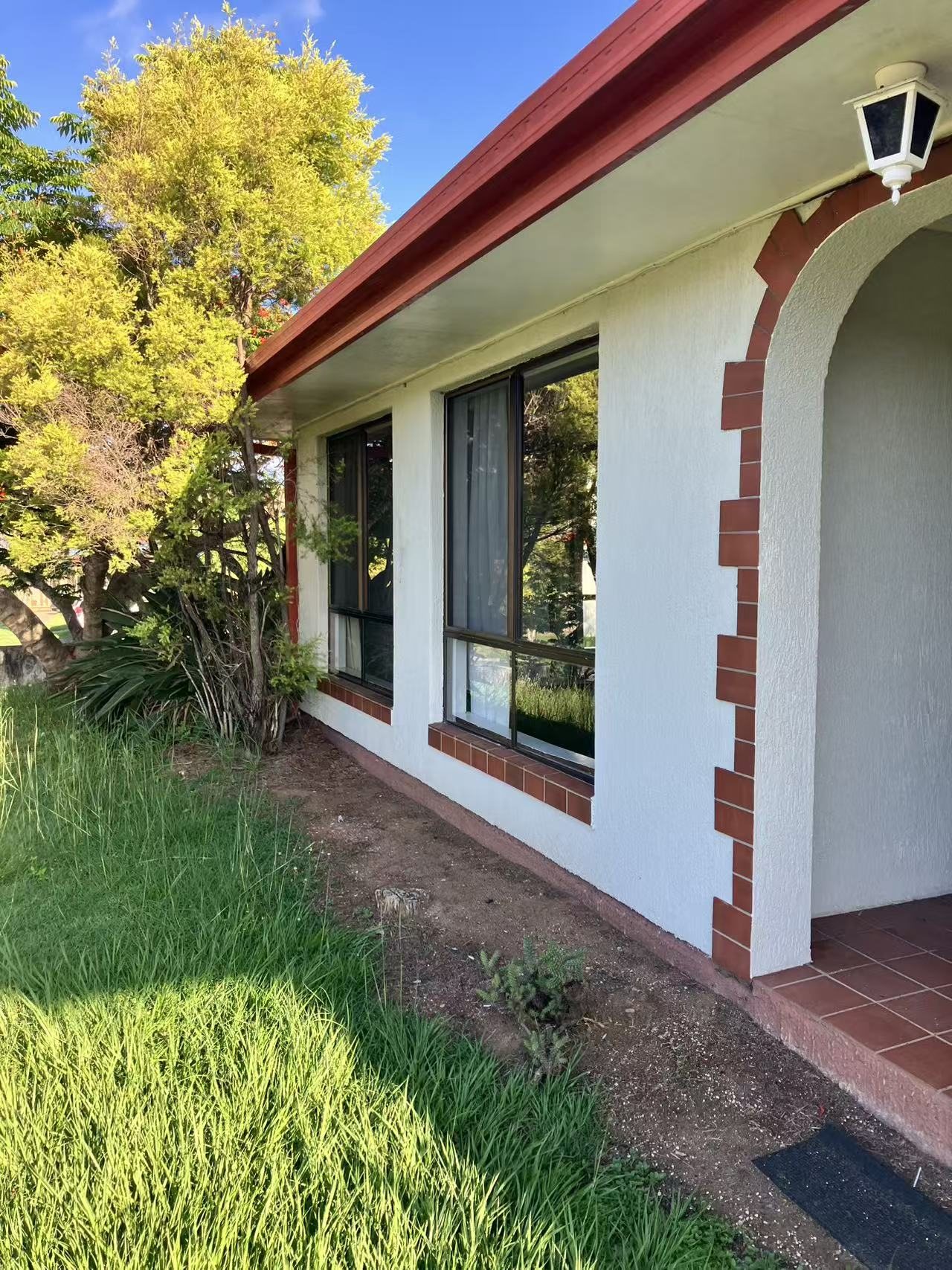 Side elevation of the home with flyscreens installed across the windows.