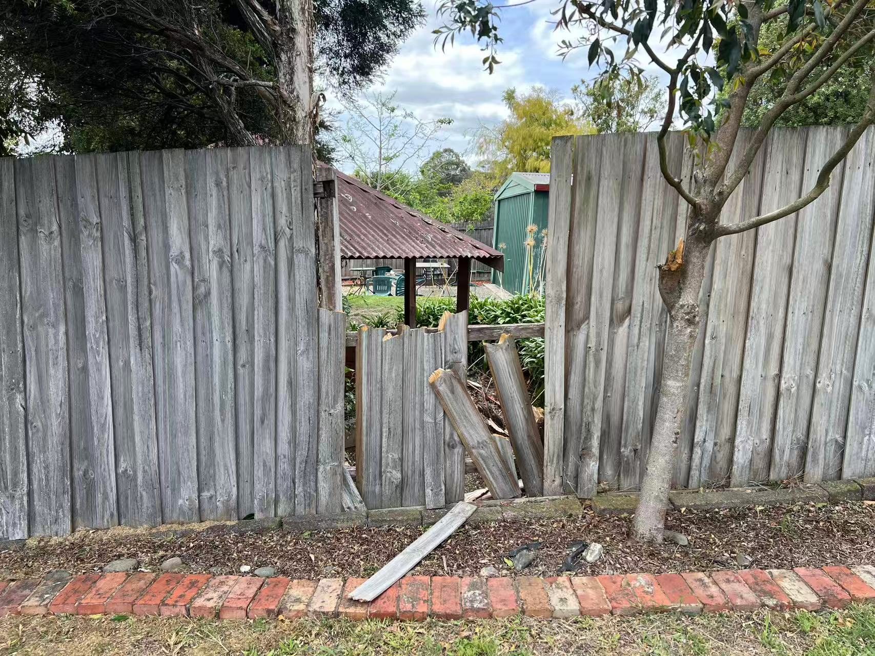 Close-up of a damaged section of the timber fence with broken palings.