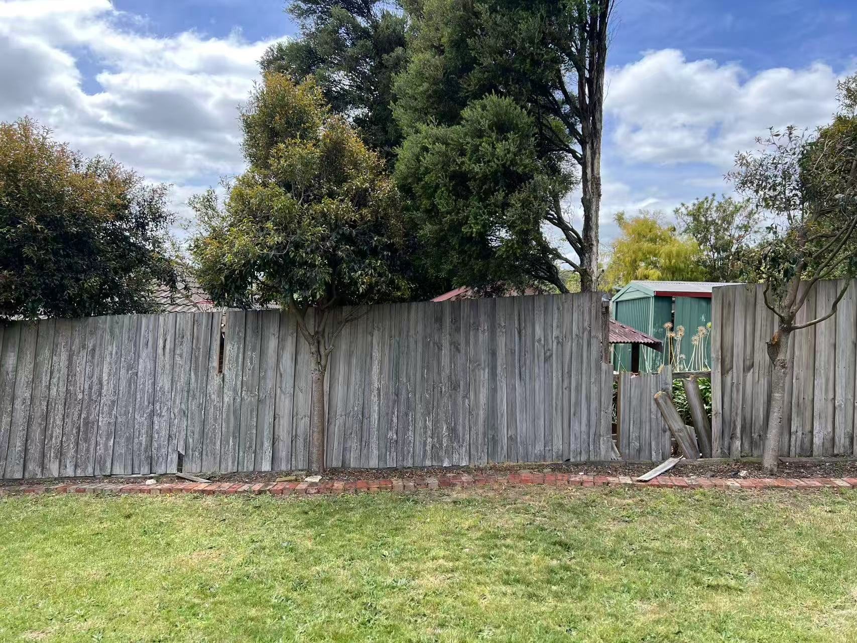 Wide view of an existing weathered timber boundary fence before repair.